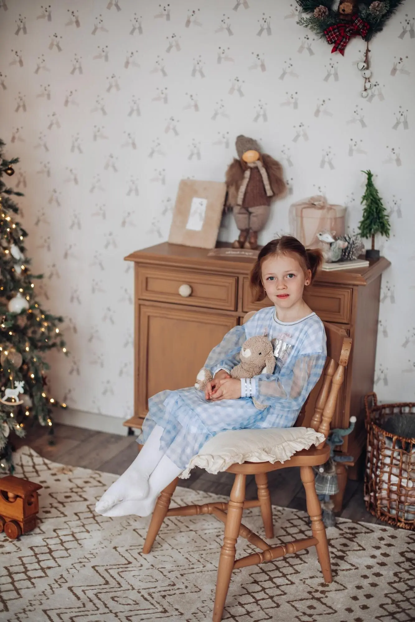 Süßes Baby-Mädchen in einem schönen Kleid neben dem Weihnachtsbaum am Familientag.